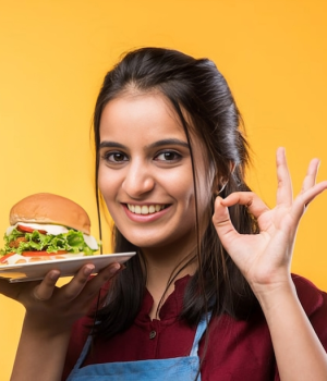 attractive-indian-asian-girl-eating-burger-white-yellow-background_466689-55082